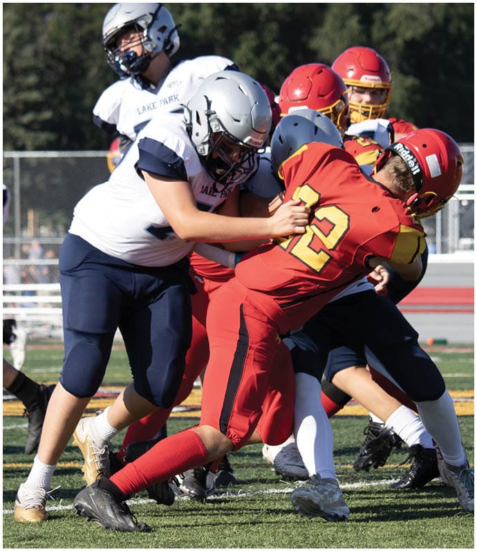 Three football players in blue and white uniforms running on a field. Description generated by AI