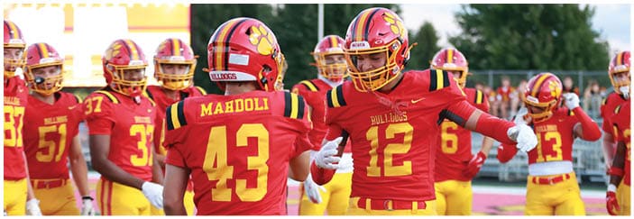 A football game is taking place on a field with players wearing blue and white uniforms. Description generated by AI