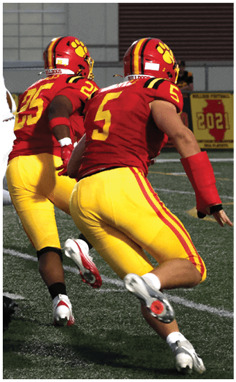 Two football players wearing blue and white uniforms. Description generated by AI