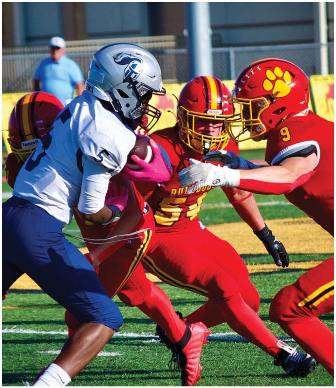 Three football players in blue and white uniforms running on a field. Description generated by AI