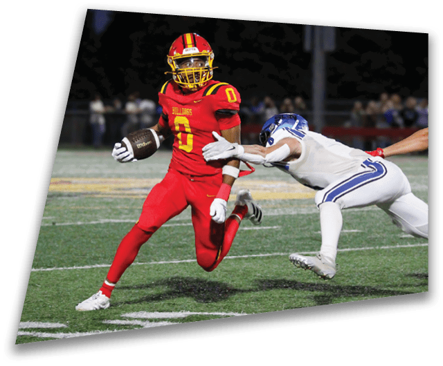 Four people in dark football uniforms and helmets stand in a row on a field, appearing focused and ready for action. Description generated by AI