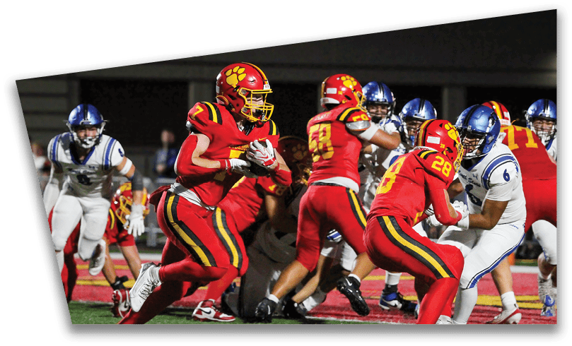 People wearing black American Canyon football uniforms and helmets are standing on a football field at night. Description generated by AI