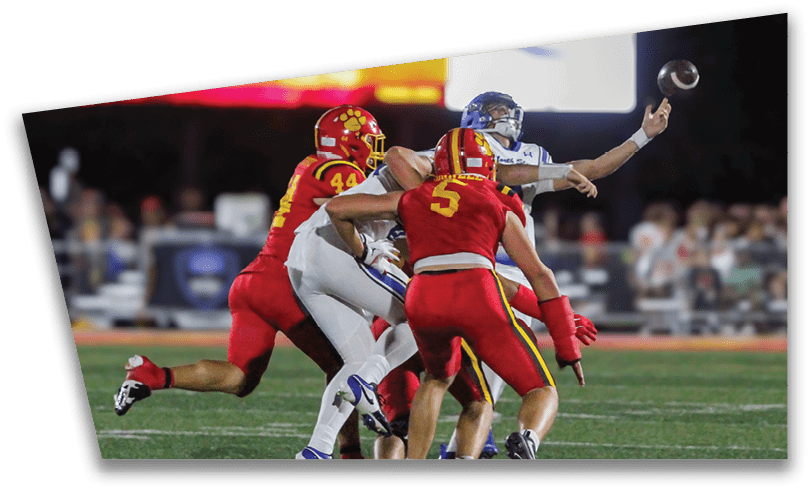 People wearing black American Canyon football uniforms and helmets are standing on a football field at night. Description generated by AI