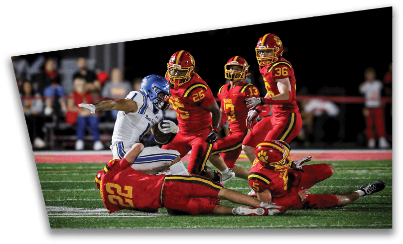 People wearing black American Canyon football uniforms and helmets are standing on a football field at night. Description generated by AI
