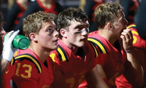 Two men wearing football uniforms are hugging each other on a field. AI generated content