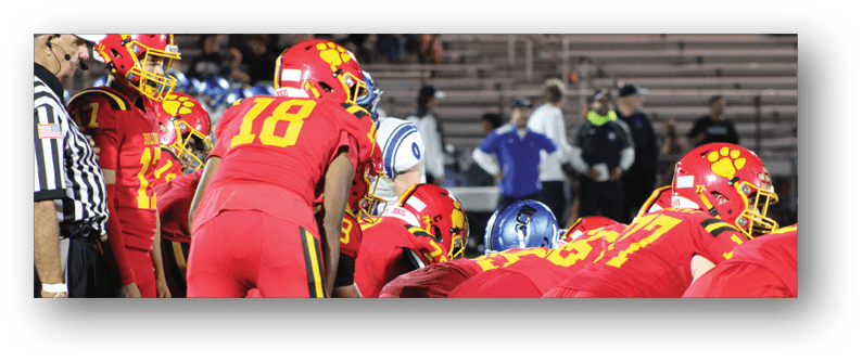 A football game is taking place on a field with players wearing blue and white uniforms. Description generated by AI