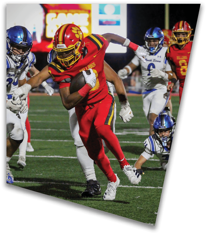 A person wearing a dark football uniform and helmet with “American Canyon" on the jersey is kneeling on one knee on a field at night. Description generated by AI