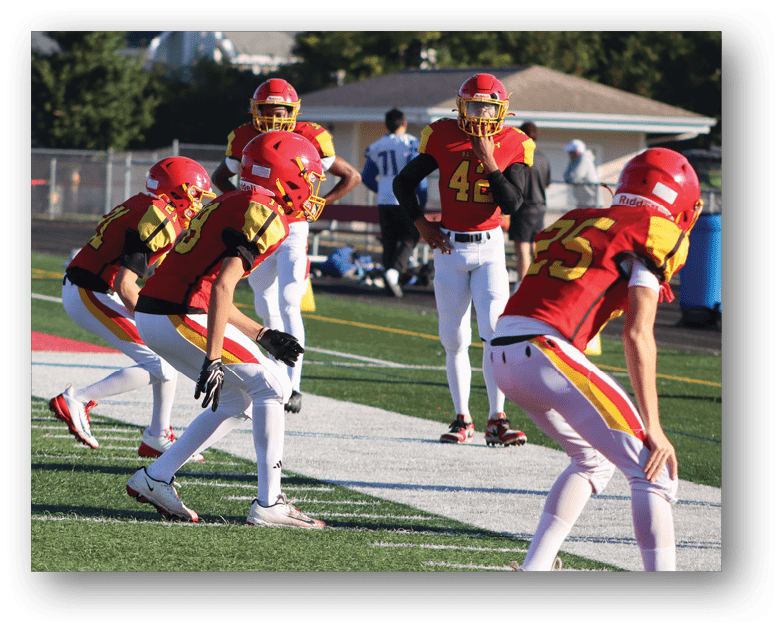 Three football players in blue and white uniforms running on a field. Description generated by AI