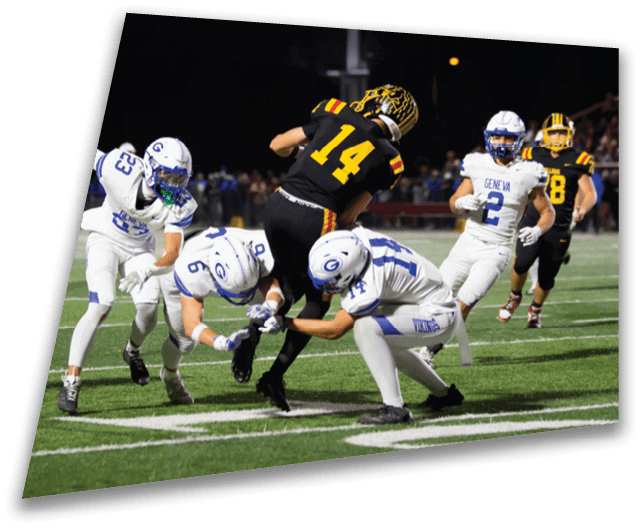 Four people in dark football uniforms and helmets stand in a row on a field, appearing focused and ready for action. Description generated by AI