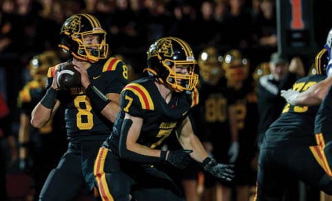 Two men wearing football uniforms are hugging each other on a field. AI generated content