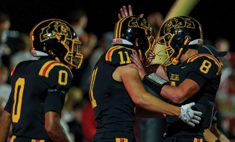 Two men wearing football uniforms are hugging each other on a field. AI generated content