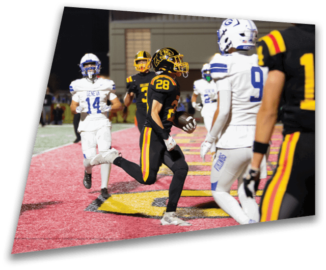 Four people in dark football uniforms and helmets stand in a row on a field, appearing focused and ready for action. Description generated by AI