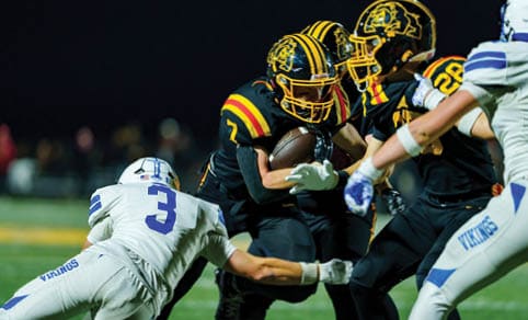 Two men wearing football uniforms are hugging each other on a field. AI generated content