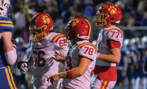 Two men wearing football uniforms are hugging each other on a field. AI generated content
