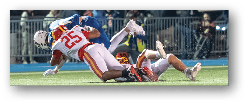 A football game is taking place on a field with players wearing blue and white uniforms. Description generated by AI