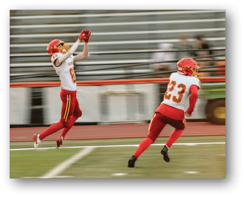 Three football players in blue and white uniforms running on a field. Description generated by AI
