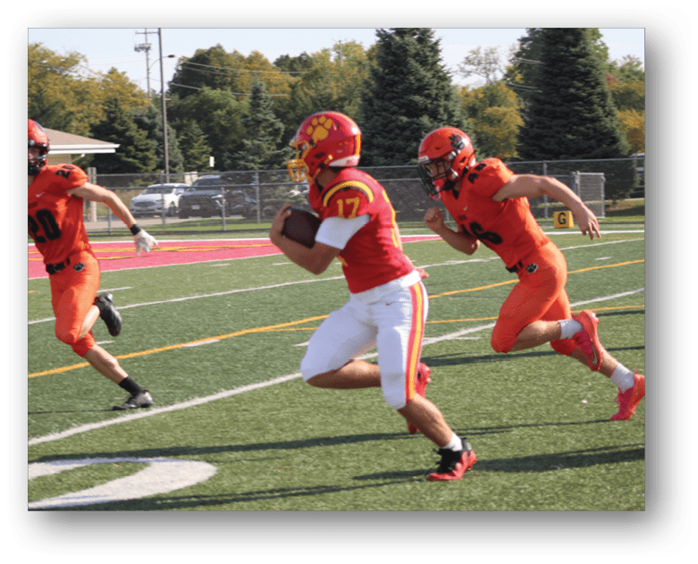 Three football players in blue and white uniforms running on a field. Description generated by AI