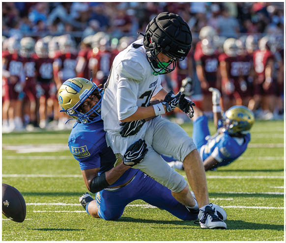 A football player in a blue uniform tackles another player. Description generated by AI