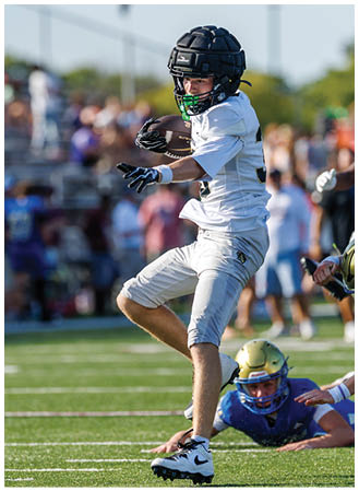 A boy in a white shirt and black helmet is running on a field. Description generated by AI