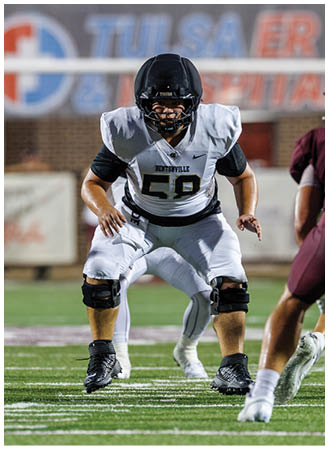 A football player in a white jersey is running on the field. Description generated by AI