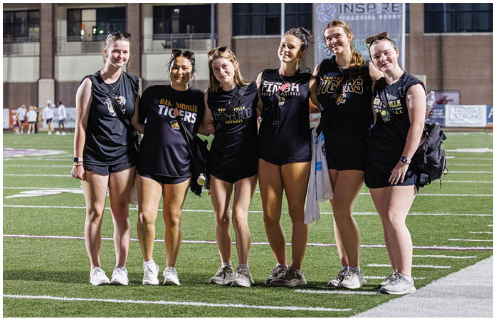 A group of cheerleaders in black and yellow shirts. Description generated by AI