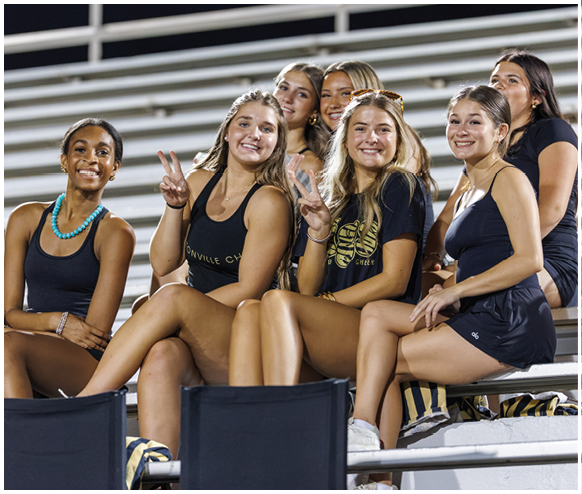A group of girls sitting on bleachers. Description generated by AI