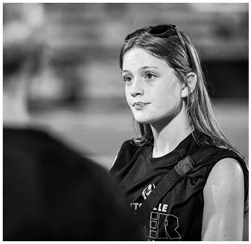 A girl wearing a black shirt with the word “Trojans" on it. Description generated by AI