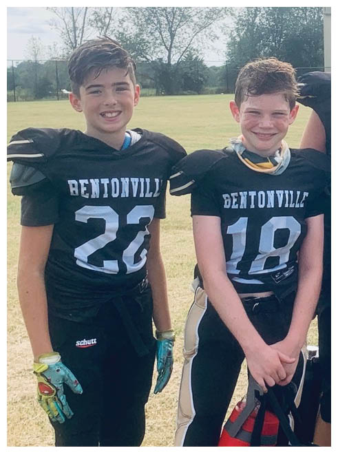 Three boys wearing football uniforms. Description generated by AI