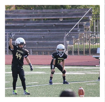 A boy wearing a football uniform is standing on a field. Description generated by AI