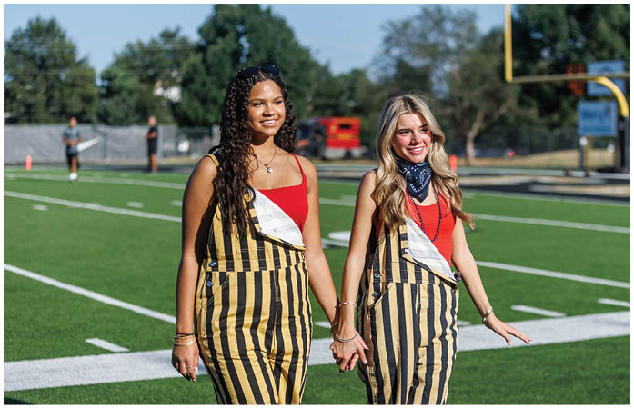 Two women wearing striped pants and red shirts. Description generated by AI