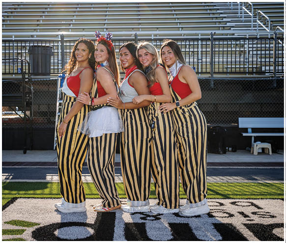 Five women wearing striped pants and red shirts. Description generated by AI