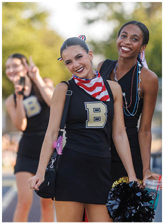 A group of cheerleaders wearing black and white uniforms. Description generated by AI