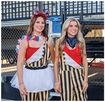 Two women wearing matching striped overalls. Description generated by AI