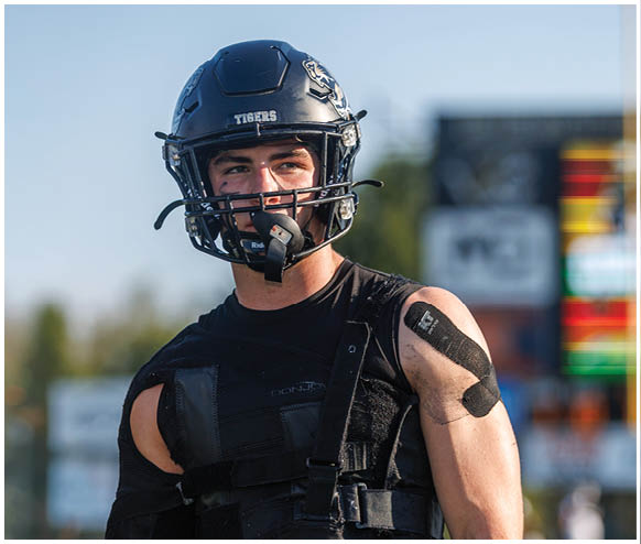 A man wearing a football helmet and shoulder pads. Description generated by AI