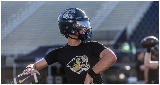 A football player wearing a black helmet and a black and white jersey. Description generated by AI