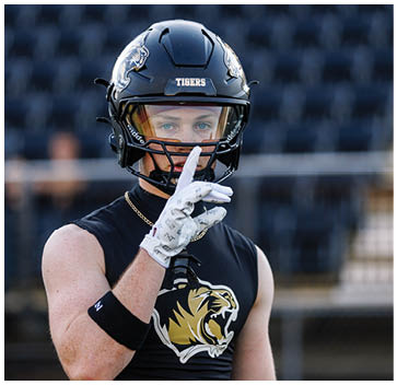 A football player wearing a black helmet with a white stripe. Description generated by AI