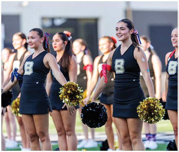 A group of cheerleaders in black and gold uniforms. Description generated by AI