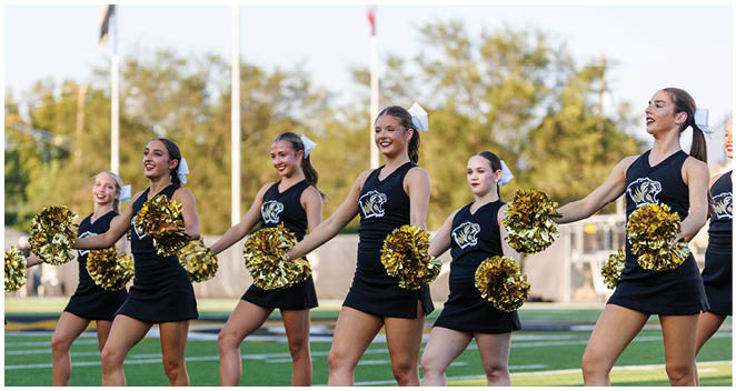 A group of cheerleaders in uniforms and pom poms. Description generated by AI