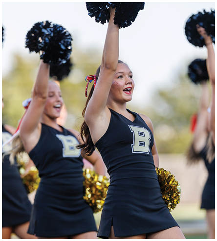 Two cheerleaders in uniforms with one holding a pom pom. Description generated by AI