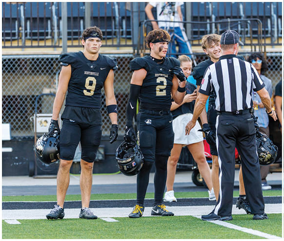 A group of football players standing on the field. Description generated by AI