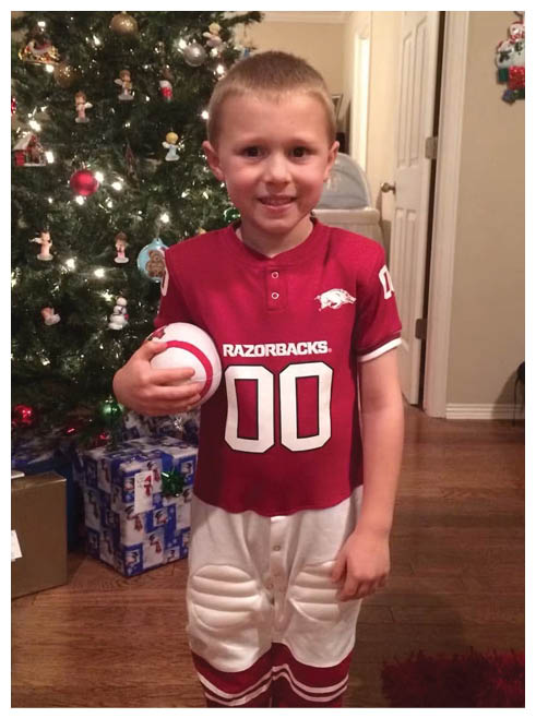 A young boy wearing a red and white jersey with the number 0 on it. Description generated by AI
