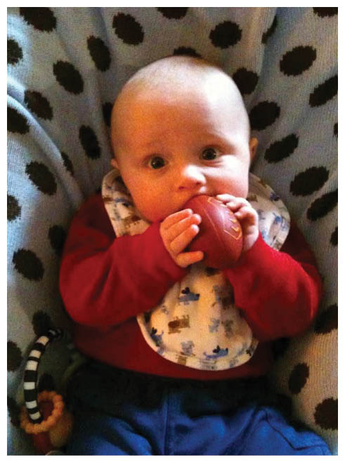 A baby wearing a red shirt and a blue bib with a white polka dot pattern. Description generated by AI