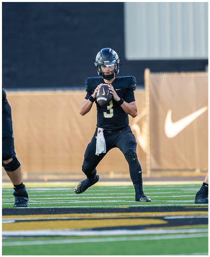 A football game is being played with a man holding a football. Description generated by AI