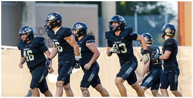 A group of football players running on a field. Description generated by AI