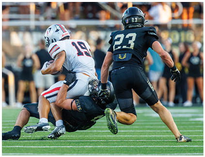 A football player is tackled to the ground. Description generated by AI