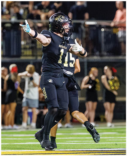 A football player wearing a black jersey with the number 11 on it. Description generated by AI