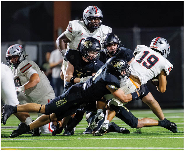 A football player is tackled to the ground. Description generated by AI