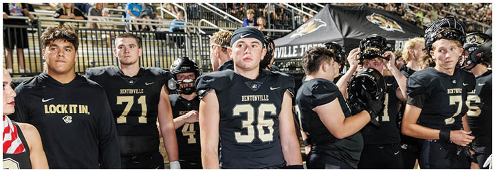 A group of football players standing on the field. Description generated by AI