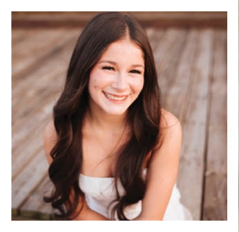 A woman with long hair and a white top is smiling. Description generated by AI