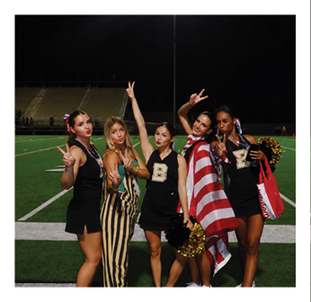 Four cheerleaders pose for a picture on a football field. Description generated by AI